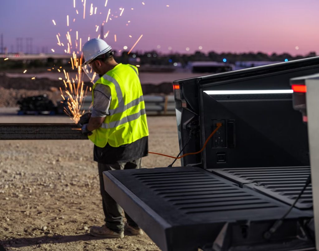 Hombre trabajando conectado a Cybertruck. Foto por Tesla